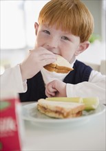 Portrait of boy (8-9) eating sandwich. Photo : Jamie Grill Photography