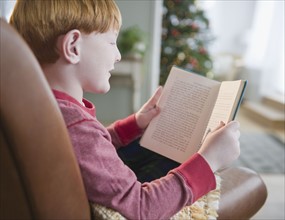 Boy (8-9) reading book on Christmas Eve. Photo : Jamie Grill Photography