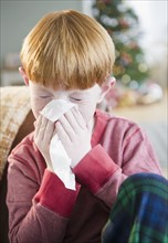 Boy (8-9) Sneezing into tissue. Photo : Jamie Grill Photography