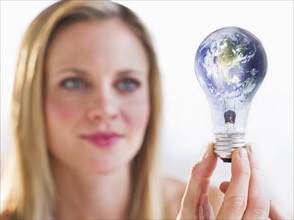 Woman holding lightbulb with globe. Photo : Daniel Grill