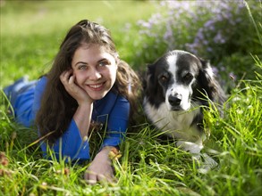USA, Colorado, Portrait of young woman relaxing with dog on grass. Photo : John Kelly