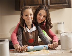 Portrait of two sisters (6-7, 18-19) rolling dough. Photo : Mike Kemp
