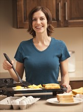 Portrait of woman preparing breakfast in kitchen. Photo : Mike Kemp