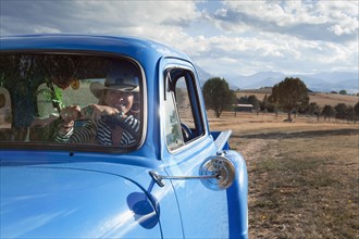 USA, Colorado, Carbondale, Cowgirl driving old fashioned pickup truck in field. Photo : Noah