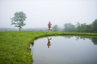 USA, Vermont, Landgrove, Woman jogging by lake. Photo : Noah Clayton