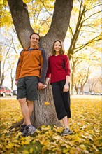 USA, Montana, Kalispell, Happy couple standing and holding hands in autumn. Photo : Noah Clayton