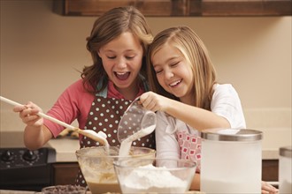 Two girls (10-11) baking in kitchen. Photo : Mike Kemp
