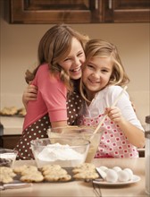Portrait of two girls (10-11) baking in kitchen. Photo : Mike Kemp