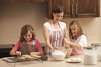 Mother baking with daughters (10-11) in kitchen. Photo : Mike Kemp