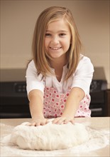 Portrait of girl (10-11) kneading dough in kitchen. Photo : Mike Kemp