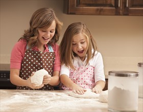 Two girls (10-11) kneading dough in kitchen. Photo : Mike Kemp