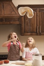 Two girls (10-11) tossing dough in kitchen. Photo : Mike Kemp