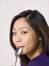 Young woman chewing spoon. Photo : Dan Bannister