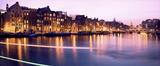 Netherlands, Amsterdam, Illuminated buildings by canal. Photo : Henryk Sadura