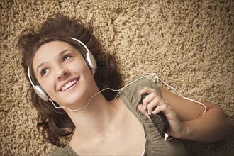 Young woman listening music from mp3 player. Photo : Mike Kemp