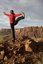 USA, Utah, Canyonlands National Park, woman stretching on rock. Photo : Noah Clayton