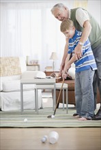 Grandfather and grandson (8-9) playing golf at home. Photo : Jamie Grill Photography