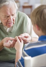 Grandfather stocking Band-Aid to grandson's (8-9) finger. Photo : Jamie Grill Photography