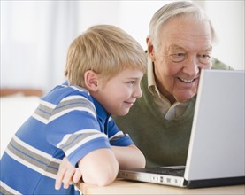 Grandfather and grandson (8-9) using laptop. Photo : Jamie Grill Photography