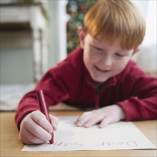 Boy (8-9) writing letter to Santa. Photo : Jamie Grill Photography