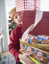 Portrait of boy (8-9) carrying Christmas gifts. Photo : Jamie Grill Photography