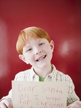 Studio portrait of boy (8-9) holding letter to Santa. Photo : Jamie Grill Photography