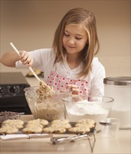 Girl (10-11) baking biscuits in kitchen. Photo : Mike Kemp