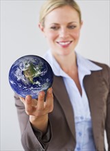 Businesswoman holding globe. Photo : Daniel Grill