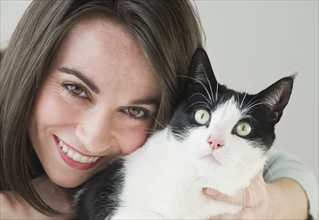 Portrait of woman hugging cat.