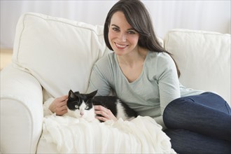 Portrait of woman with cat on sofa.
