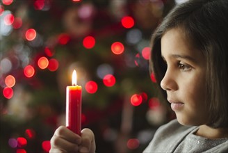 Girl (8-9) holding christmas candle.