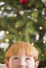 Boy (8-9) by Christmas tree. Photo : Jamie Grill Photography