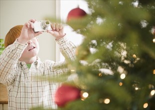 Boy (8-9) photographing Christmas tree. Photo : Jamie Grill Photography