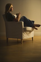 Woman sitting in armchair. Photo : Daniel Grill