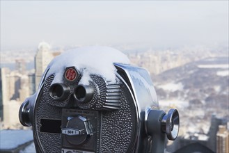 USA, New York City, Coin operated binoculars covered with snow, Central Park in background. Photo :