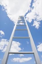 Ladder reaching cloudy sky. Photo : Chris Hackett