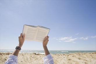 USA, Massachusetts, woman's hands on beach holding book. Photo : Chris Hackett