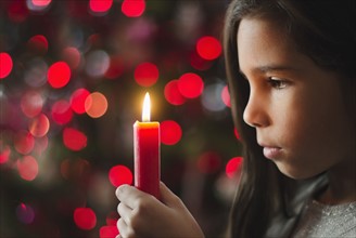 Girl (8-9) holding candle.