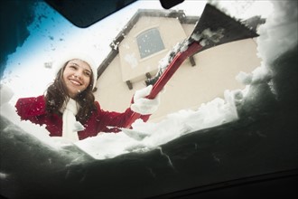 USA, Utah, Lehi, Young woman scraping snow from car windscreen. Photo : Mike Kemp
