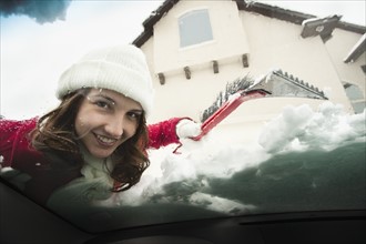 USA, Utah, Lehi, Portrait of young woman scraping snow from car windscreen. Photo : Mike Kemp