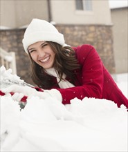 USA, Utah, Lehi, Portrait of young woman scraping snow from car. Photo : Mike Kemp