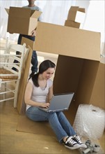Woman using laptop by cardboard box.