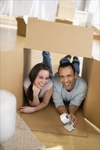 Couple lying inside cardboard box.