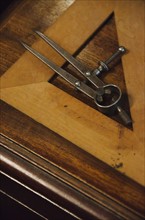 Antique set square and pair of compasses on wooden table.