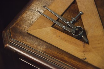 Antique set square and pair of compasses on wooden table.