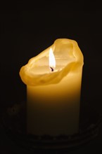 Illuminated candle on black background.