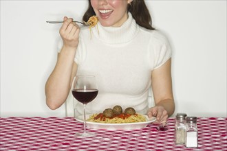 Happy woman eating spaghetti, studio shot.