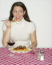 Portrait of woman eating spaghetti with meatballs.