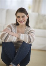Portrait of attractive young woman sitting on floor.