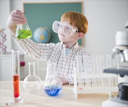 Boy (8-9) holding chemical flask in science lab. Photo : Jamie Grill Photography